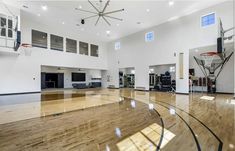 an indoor basketball court with hard wood flooring and white walls in the middle of it