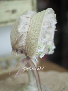 a white hat is sitting on top of a glass vase with flowers in the background