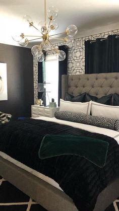 a bedroom with black and white bedding, chandelier and curtains