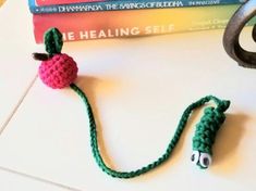 there is a crocheted apple on the table next to some books and scissors