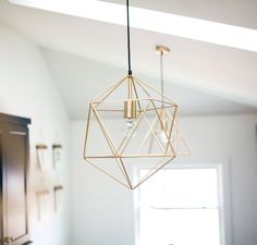 a light fixture hanging from the ceiling in a room with white walls and wood floors