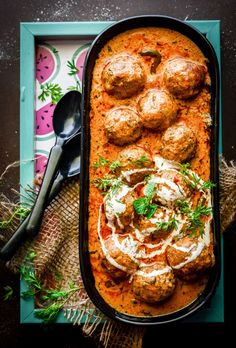 meatballs and sauce in a baking dish with spoons on the side, ready to be eaten