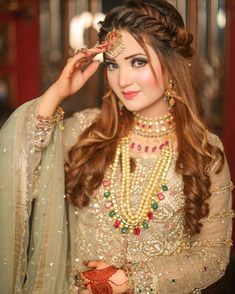 a woman in a bridal outfit posing for the camera with her hands on her head