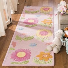 two stuffed animals sitting on the floor next to a pink rug with flowers and leaves