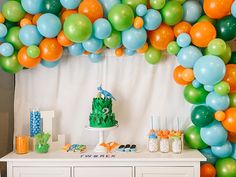 a table topped with lots of balloons and cake