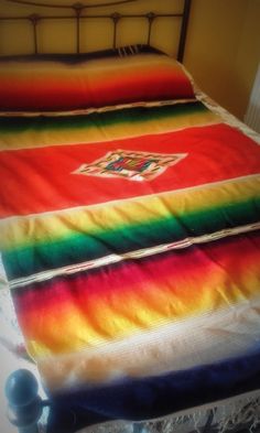 a bed with a rainbow blanket on top of it