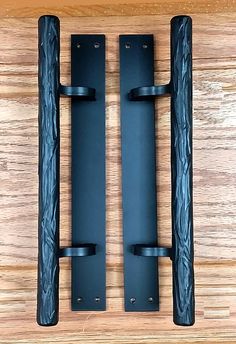 two black door handles on a wooden surface with the same design as each one, and different sizes