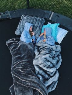 a woman laying on top of a black trampoline covered in blankets and pillows