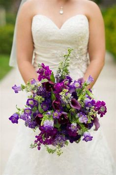 a bride holding a bouquet of purple flowers