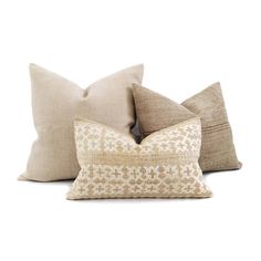 three pillows with different patterns on them, one in beige and the other in tan