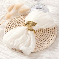 a white bag sitting on top of a table next to a wine glass and some feathers