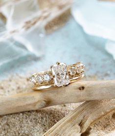 three stone ring sitting on top of a piece of driftwood