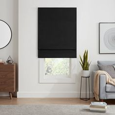 a living room with a couch, chair and window covered in black roller shades on the windowsill