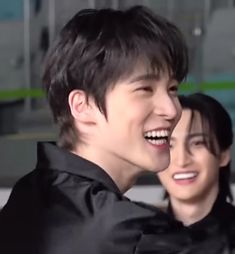 two people are smiling and one is wearing a black shirt