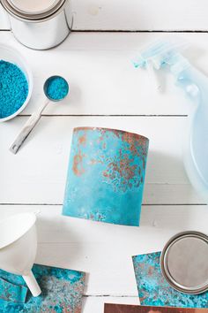 some paint and other items on a white wooden table with blue tins in them