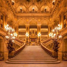 an old building with stairs and chandeliers in the center is lit by lights