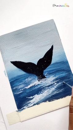 someone is painting a picture of a whale tail in the water with blue and white paint