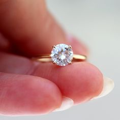 a close up of a person's hand holding a ring with a diamond in it