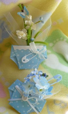 two small blue boxes with flowers in them on a yellow and green cloth covered surface