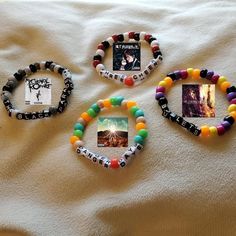 three bracelets with pictures on them are laying on a white sheet and one has an album in the middle