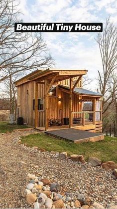 a small wooden cabin sitting on top of a hill next to some rocks and trees