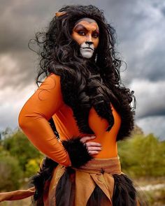 a woman dressed in an orange costume with long black hair and makeup on her face