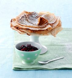 powdered sugar on top of crepes and berries in a bowl