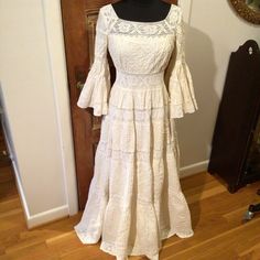 a white dress sitting on top of a wooden floor next to a mirror and door