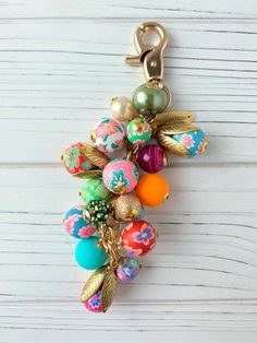 a keychain with many colorful beads and charms attached to it on a white wooden surface