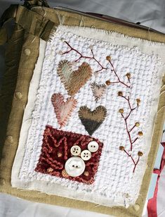 a close up of a bag on a bed with buttons and flowers in the background