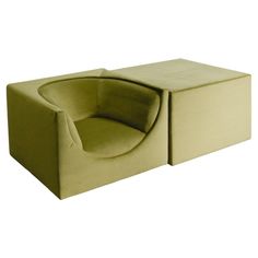 a green chair sitting on top of a white floor next to a box shaped ottoman