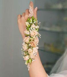 a woman wearing a wedding bracelet with flowers and pearls on her wrist is holding something in the air