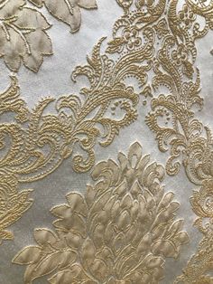 an intricate gold and silver fabric with flowers on the side, in close up view