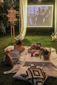 a woman sitting on the grass watching a movie