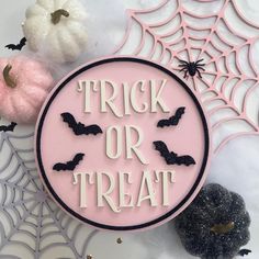 a trick or treat sign surrounded by spooky spider webs and pumpkins