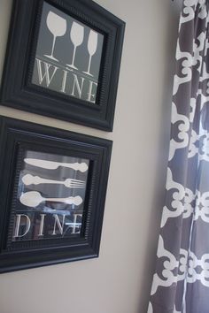 two framed pictures hang on the wall next to a window with wine glasses and utensils