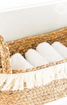 a basket filled with white towels sitting on top of a table