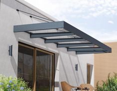 an awning on the side of a building next to a patio with chairs and table