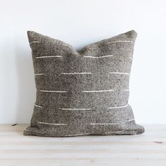 a black and white pillow sitting on top of a wooden table