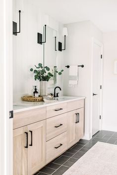 a bathroom with two sinks, mirrors and plants in vases on the counter top