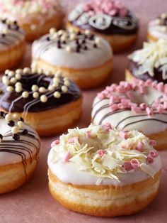 there are many donuts with different toppings on the top one is white and pink