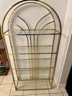 a gold metal shelf with glass shelves in the middle and tile flooring on top