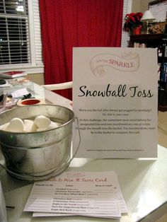 there is a sign that says snowball toss on the table next to a bucket of marshmallows