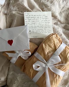 two wrapped presents are sitting next to an envelope with a heart on it and a note