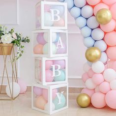 baby blocks are stacked up with balloons and flowers on the floor in front of them