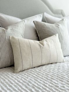 a bed with white and gray striped pillows