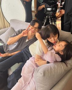 three people are sitting on a couch and one person is taking a photo with a camera