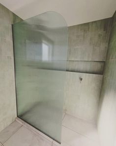 a bathroom with a glass shower door and tiled walls