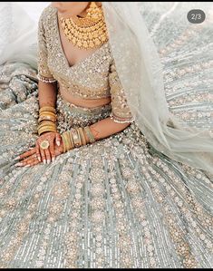 a woman in a bridal gown sitting on the ground with her hands clasped to her chest