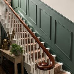 there is a wooden banister next to the stairs in this house with green painted walls